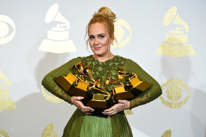 Adele poses in the Grammys press room with her five awards.