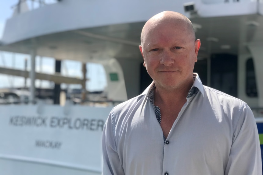 a man stands next to a ferry smiling