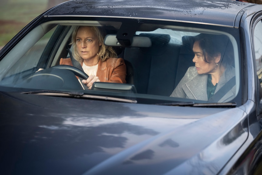 Two women sit in the front seats of a car.