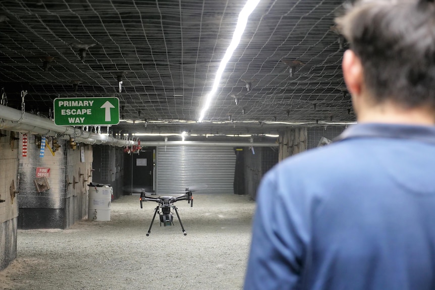 A man standing in the foregroud with a drone in focus.
