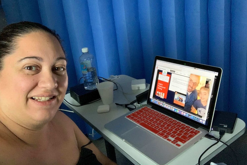 woman in hospital sitting at a laptop video calling husband and son