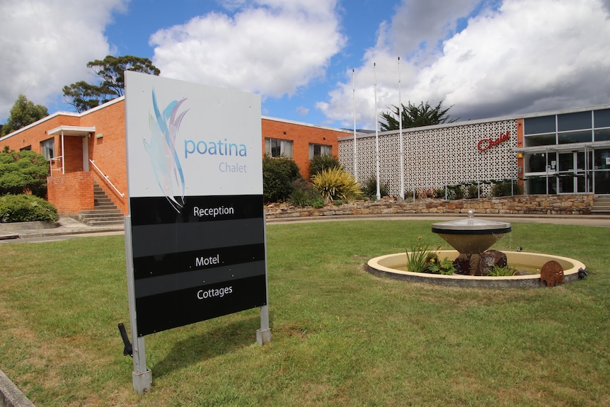 A sign stating 'Poatina Chalet'  in front of large brick building.