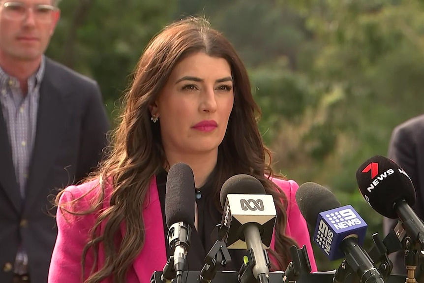 a woman standing behind microphones