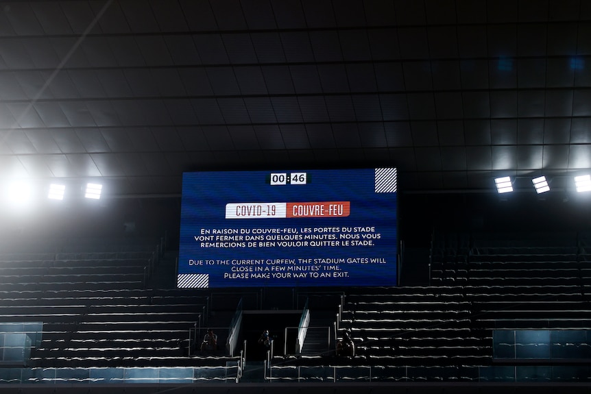 A message in French and English tells fans to leave the stadium due to a COVID curfew at the French Open.