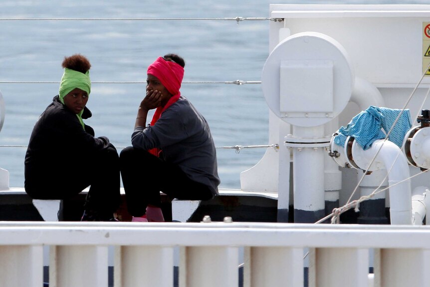 Two female migrants are seen waiting on ship.