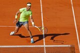 A tennis player at the French Open leans in to get his racquet to the ball near the net.