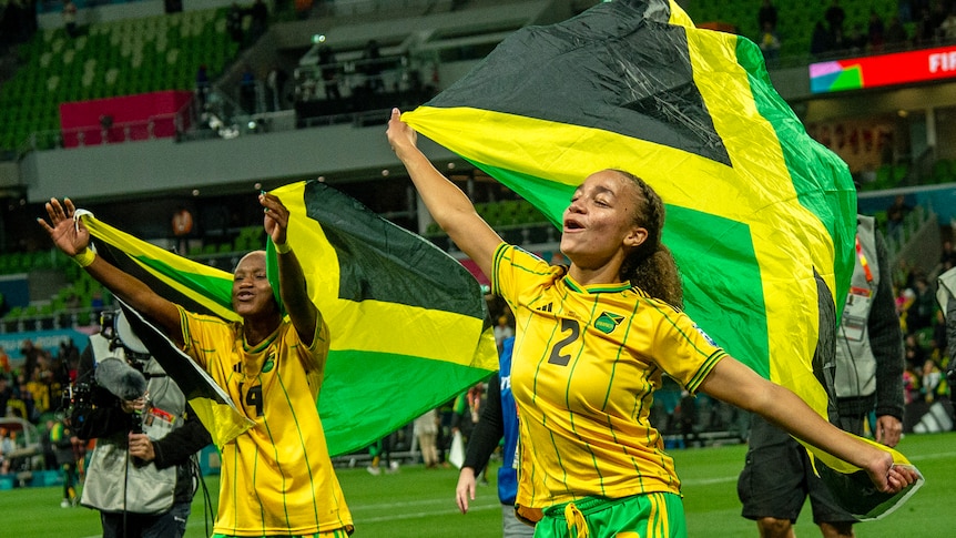 Jamaican footballers wave flags and celebrate a victory.