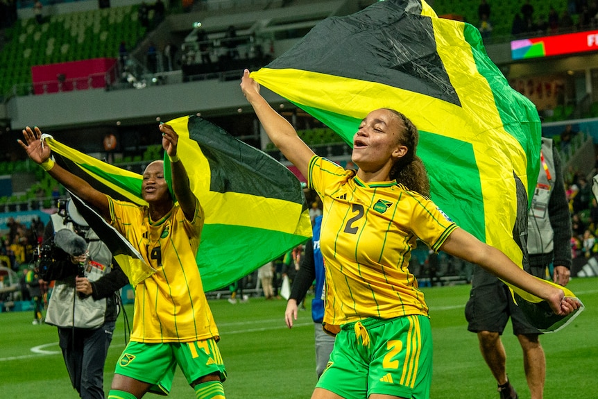 Jamaican footballers wave flags and celebrate a victory.