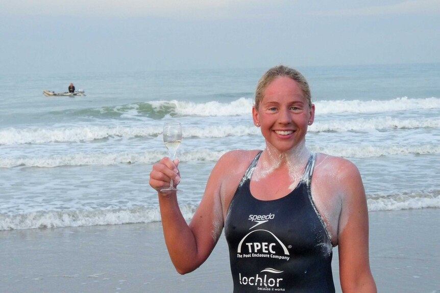Chloe McCardel holds a glass of champagne after crossing the English Channel.