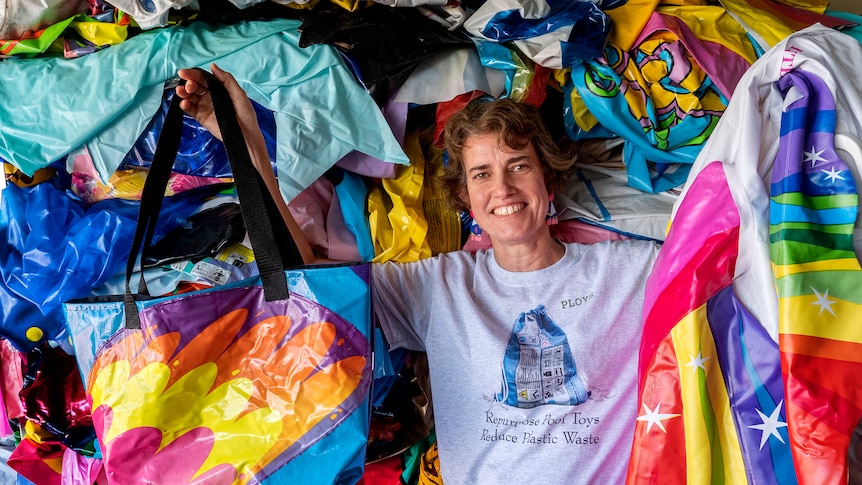 A woman holds a deflated pool float and a bag made from pool float plastic.