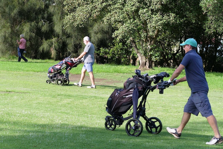 Two golfers and a walker practice social distancing at Marrickville Golf Course, April, 2020.
