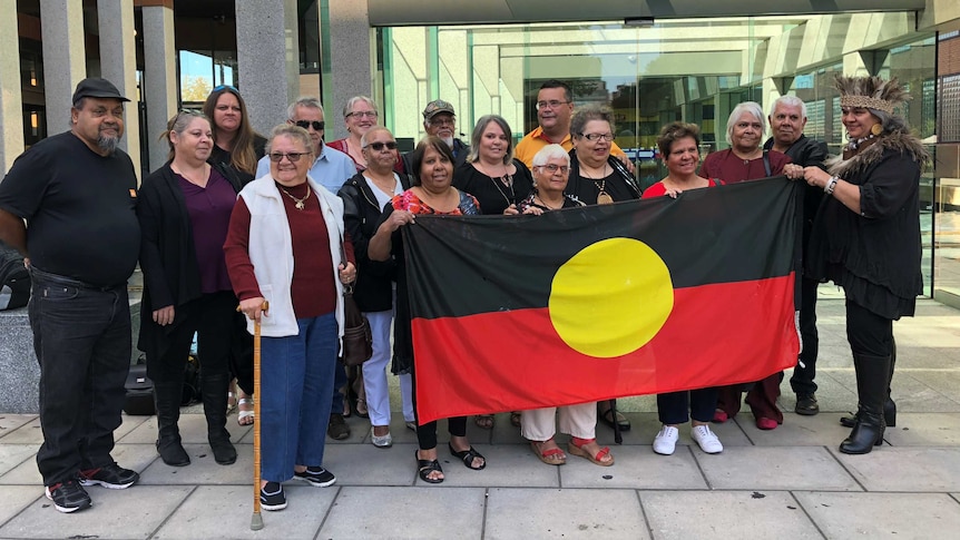 The Kaurna people hold an Aboriginal flag outside the Federal Court in Adelaide.