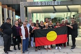 The Kaurna people hold an Aboriginal flag outside the Federal Court in Adelaide.