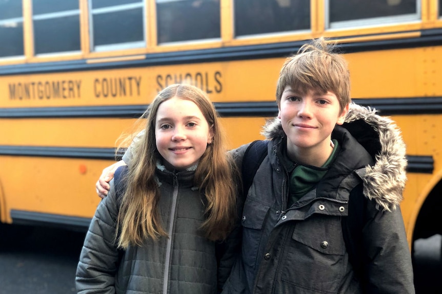 Two children standing in front of Montgomery County Schools bus with arms around each other.