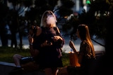 two women vaping in an outdoor space. it is shadowy and their identities can't be easily made out