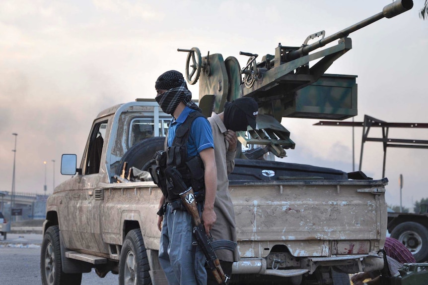 Fighters of the Islamic State of Iraq and Syria (ISIS) stand guard at a checkpoint in Mosul.