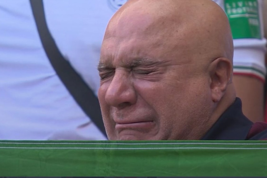 A bald man closes his eyes and cries