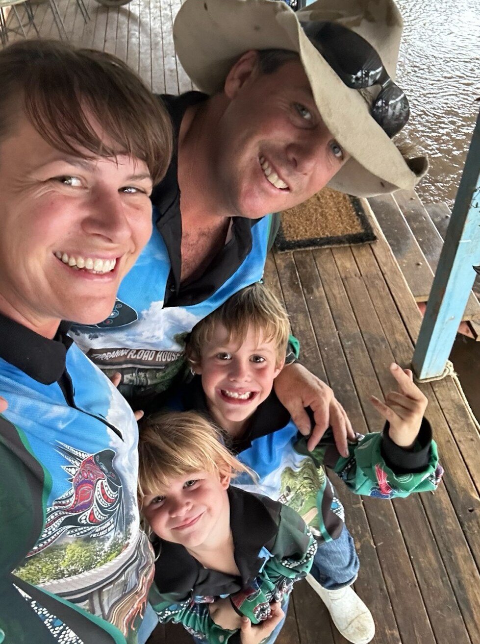 A mum, dad and young son and daughter wear fishing shirts and smile directly at the camera