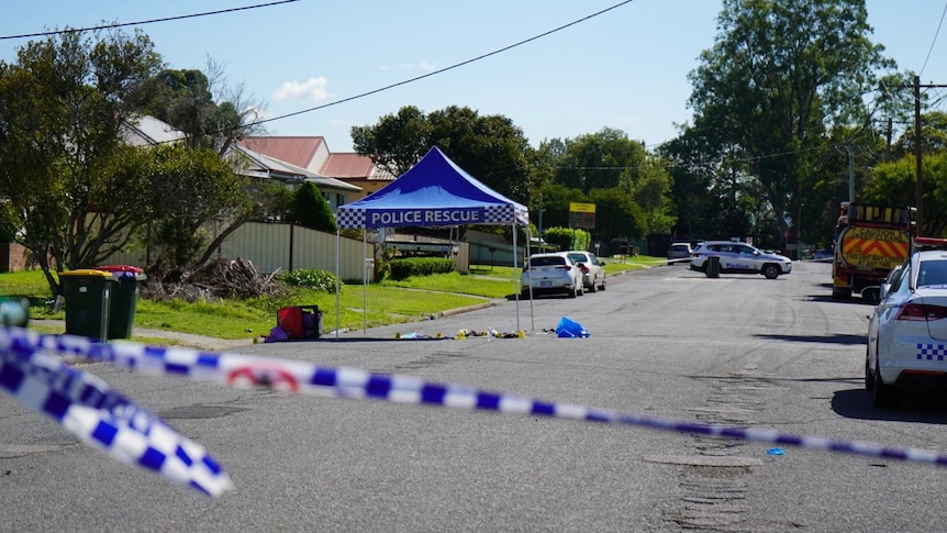 A suburban street cordoned off with police tape. A small police marquee has been set up on the side of the road.