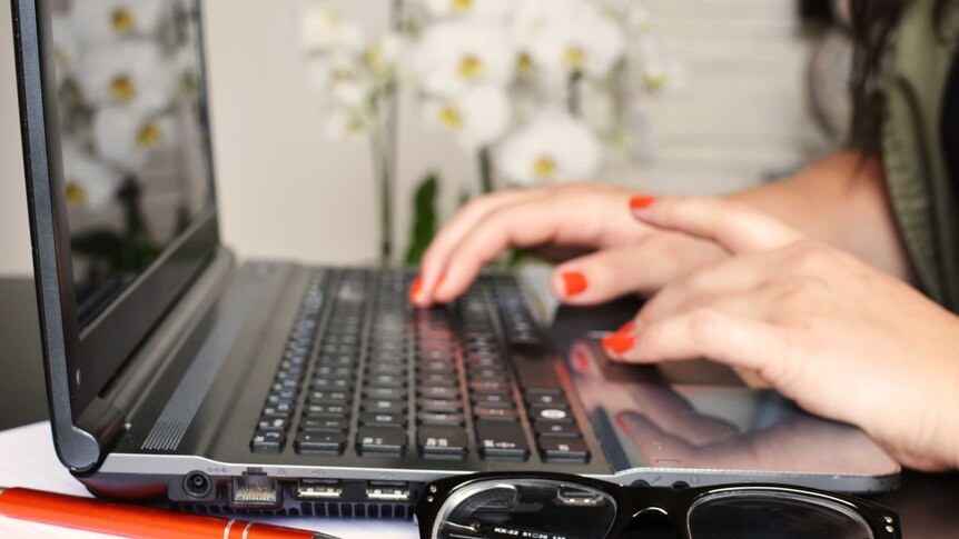 A woman types on a laptop computer.
