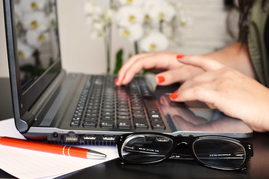 A woman types on a laptop computer.