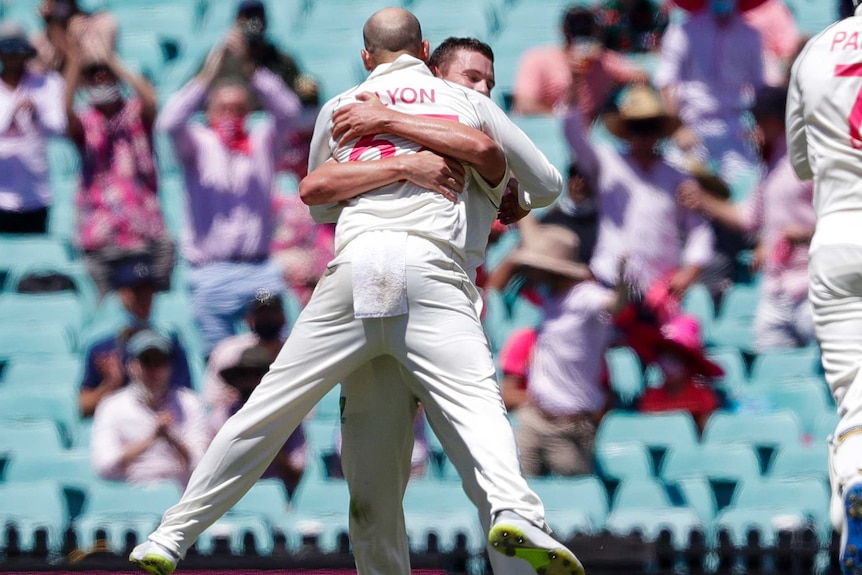 Nathan Lyon, with back to camera, leaps into the arms of a happy Josh Hazlewood