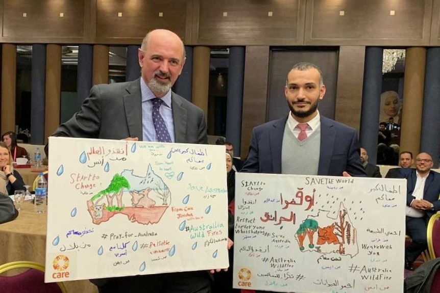 Australian ambassador, Miles Armitage standing with drawings form syrian refugee children.
