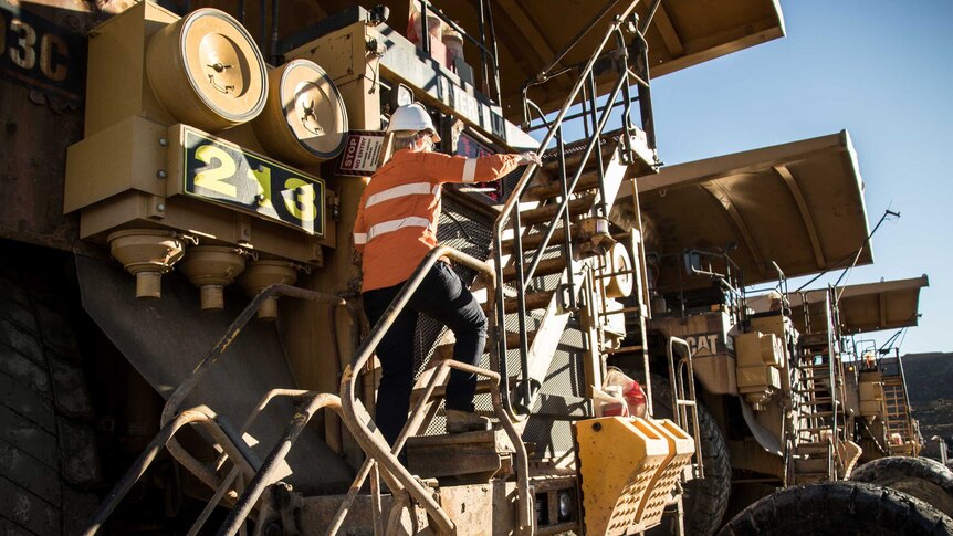 A female worker climbs into a truck at a mine site