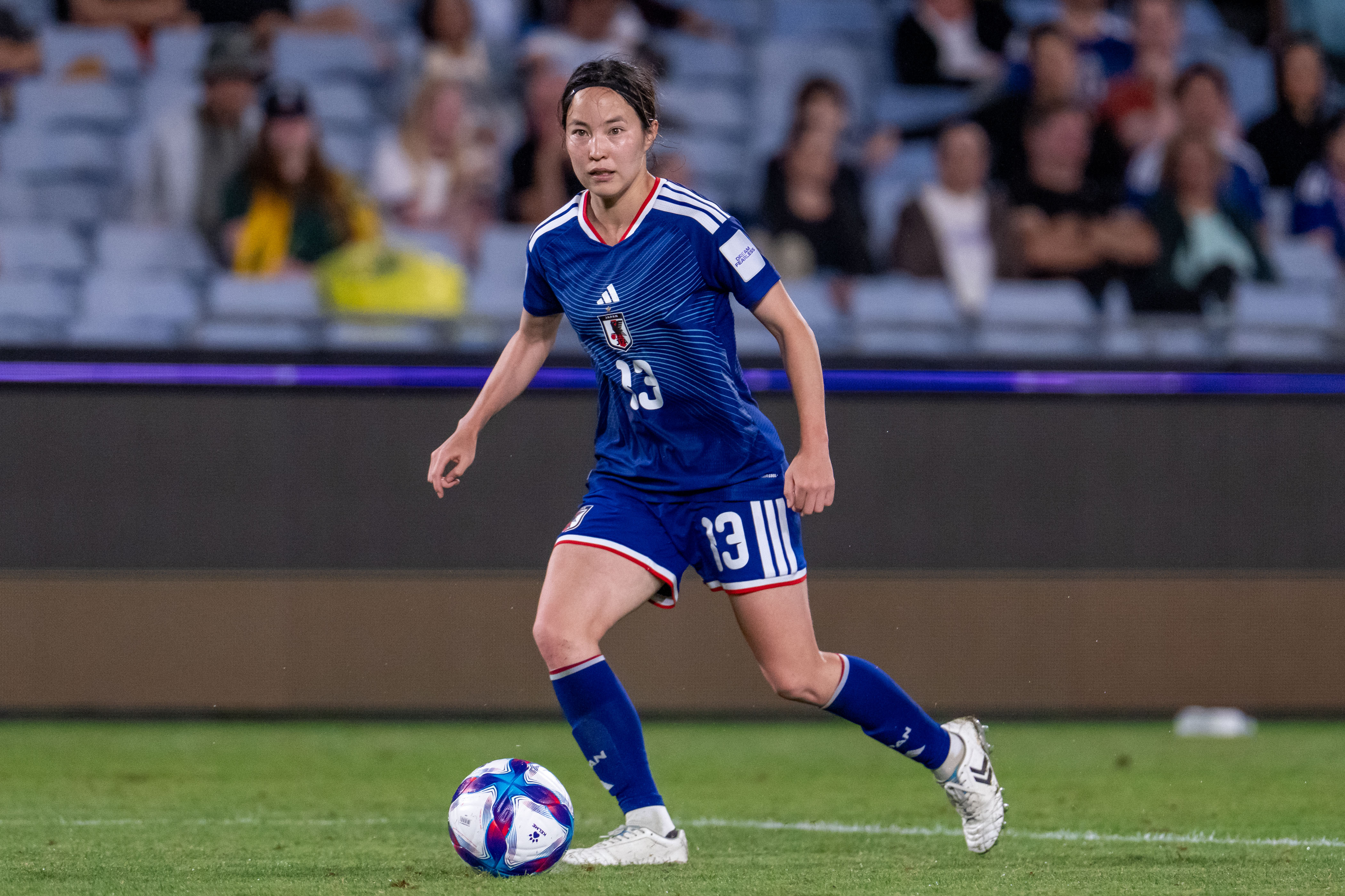 A soccer player in blue has the ball at her feet