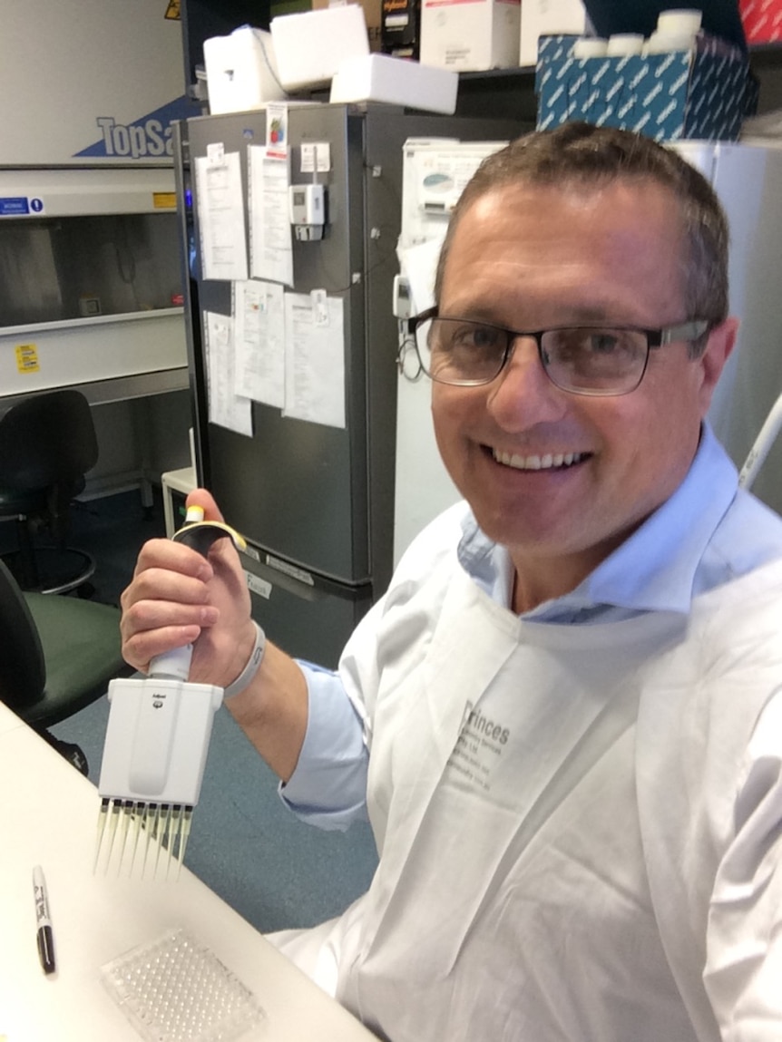 A man in a lab coat smiles