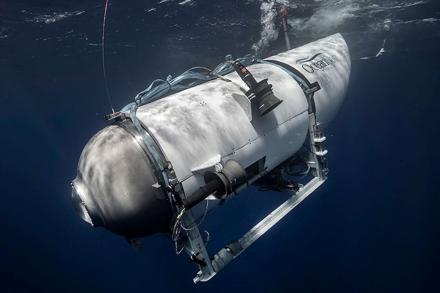 A white cylindrical submersible descends through water at an angle.