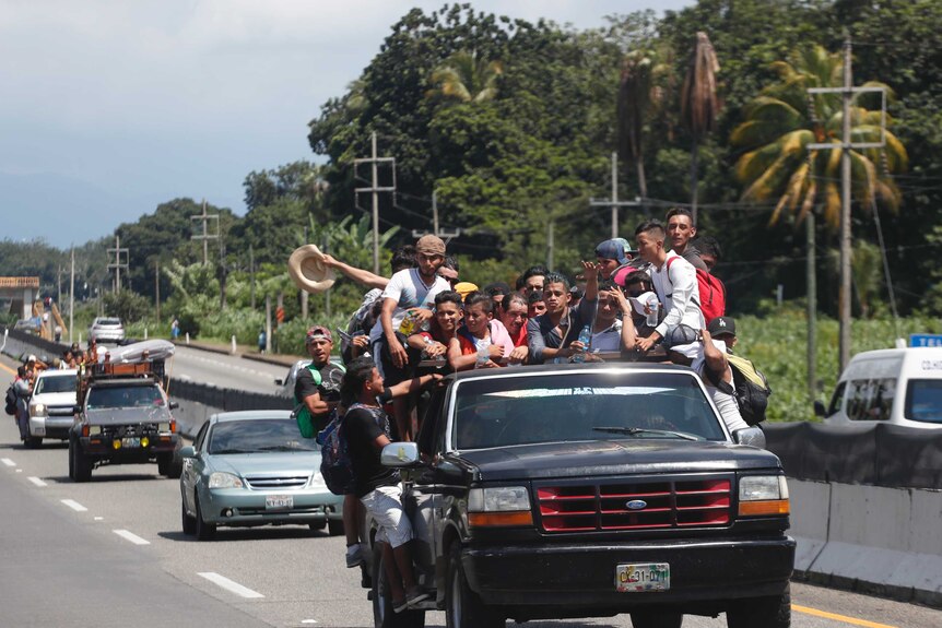 Central Americans migrants riding in the bed of a pickup truck.