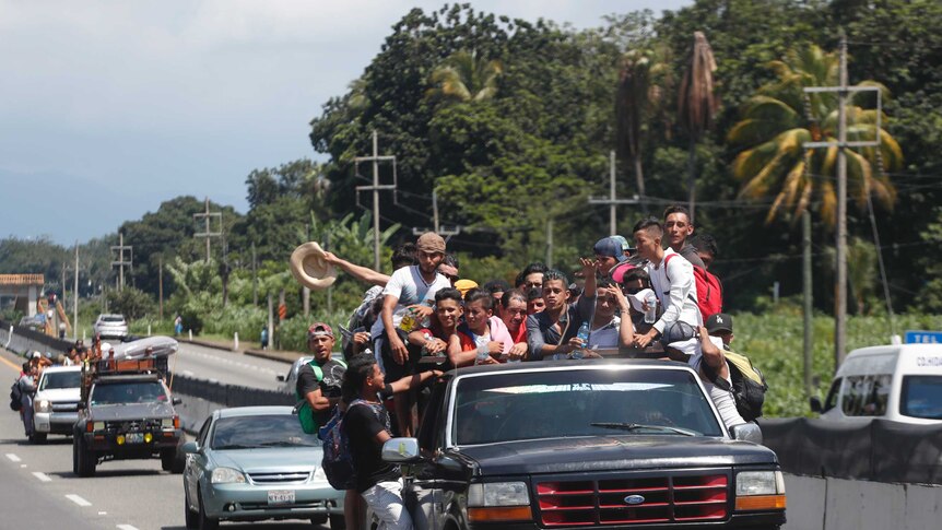Central Americans migrants riding in the bed of a pickup truck.