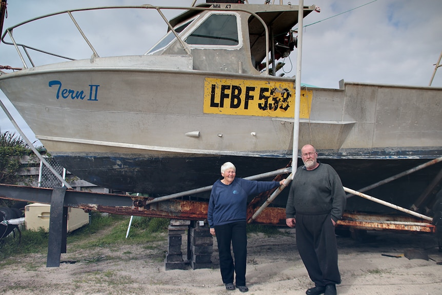 A man and a woman standing beside a fishing boat