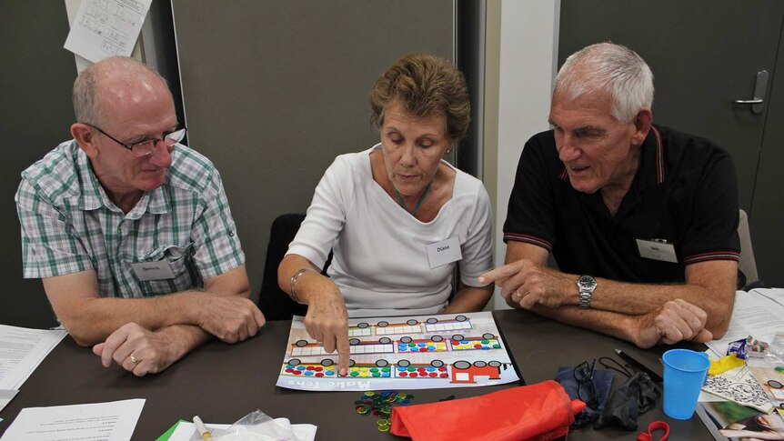 Two senior citizen males and one female play a board game.