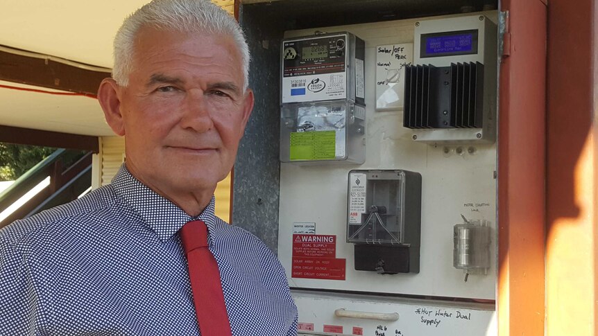 Paladin Solar Australia director Mark Robinson stands next to a meter box with a solar energy diverting device in it.