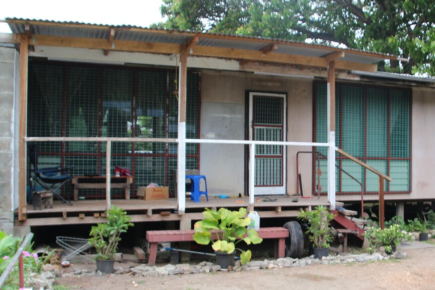 A house with a verandah and car parked on the side.
