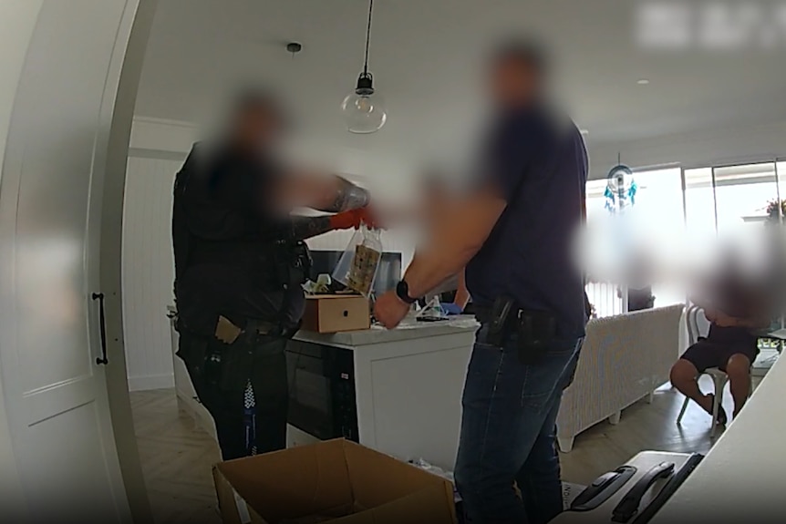 A blurred image of two police officers putting cash in a plastic bag
