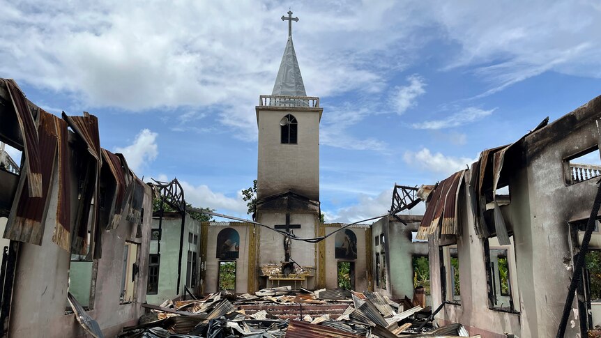 A view of a burnt church with charred walls and no roof.