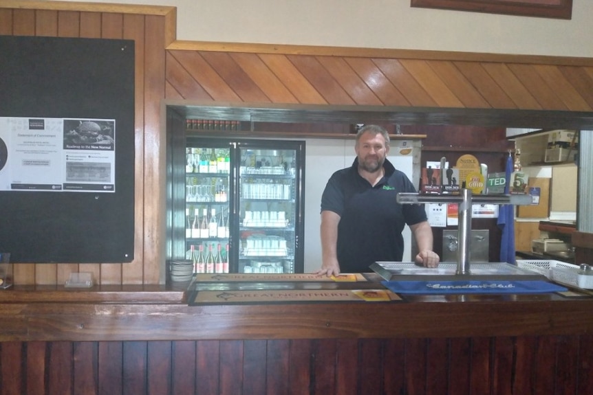 Jason Groves, the manager of the Goldfields Hotel in Tennant Creek, stands at the bar and looks at the camera.