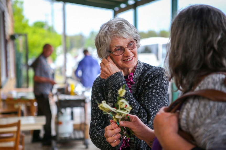 Faye Belling hands out flowers from her garden at the memorial.