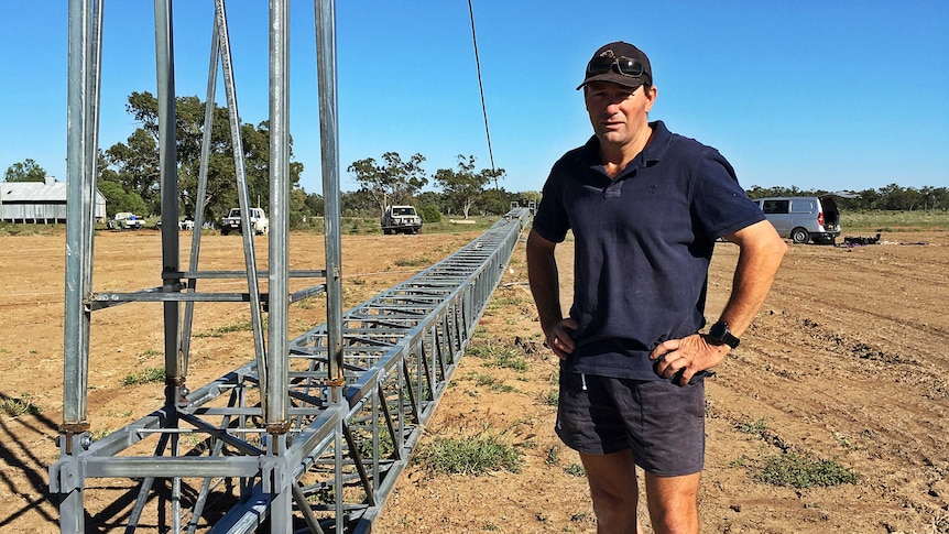 A man stands next to a horizontal wireless internet tower that is ready to be erected.