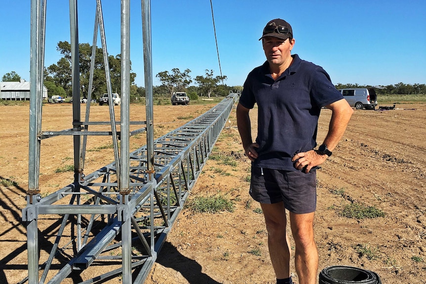 A man stands next to a horizontal wireless internet tower that is ready to be erected.