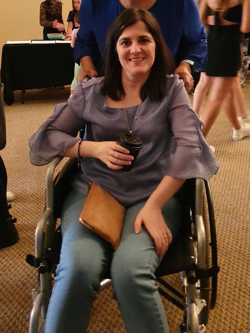 Woman with dark hair smiling, sitting in wheelchair