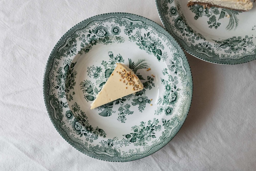 Slice of honey cheesecake on a patterned plate, topped with bee pollen and dried thyme, a light and creamy summer dessert recipe
