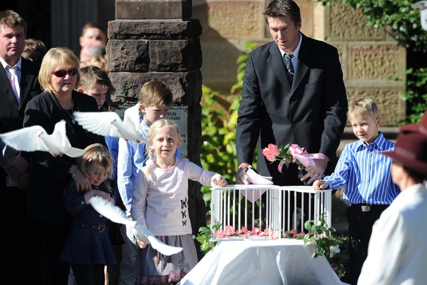 Glenn McGrath, along with his children Holly and James, release three white doves