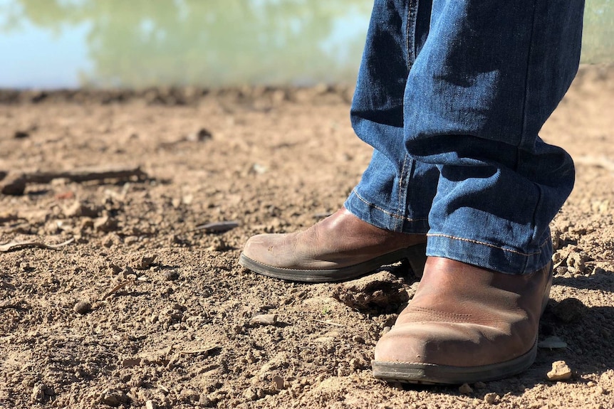 Closeup of boots in the dry dust near a dam