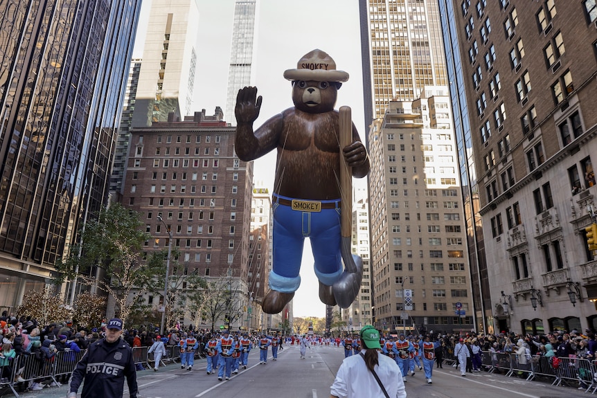 Handlers pull the Smokey Bear balloon down Sixth Avenue