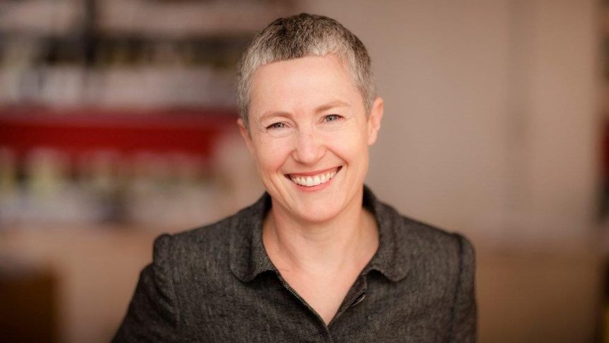 Kate Colvin, national spokesperson for Everybody's Home, in a black shirt with short grey hair smiles at the camera