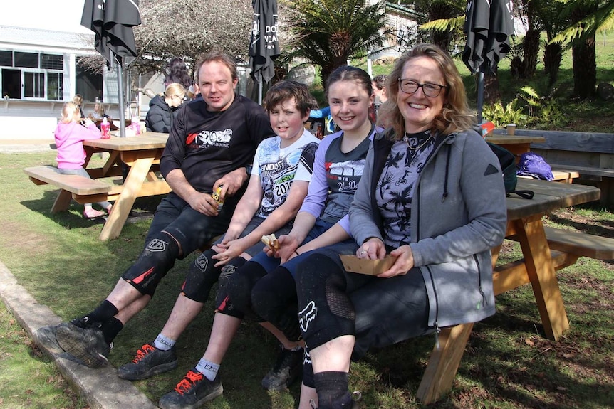 Rachel Brown and family sit on a bench outside.